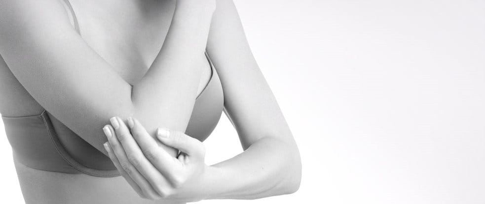 Woman wearing a bra touching her elbow