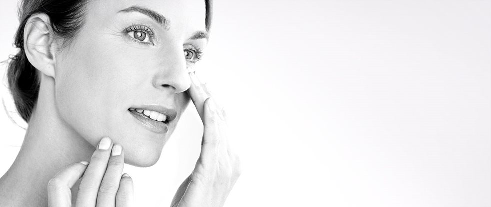 Woman applying cream on her cheek.