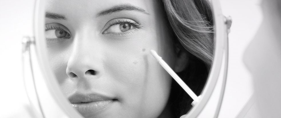 Woman applying Eucerin Even Brighter Spot Corrector while watching herself in the mirror