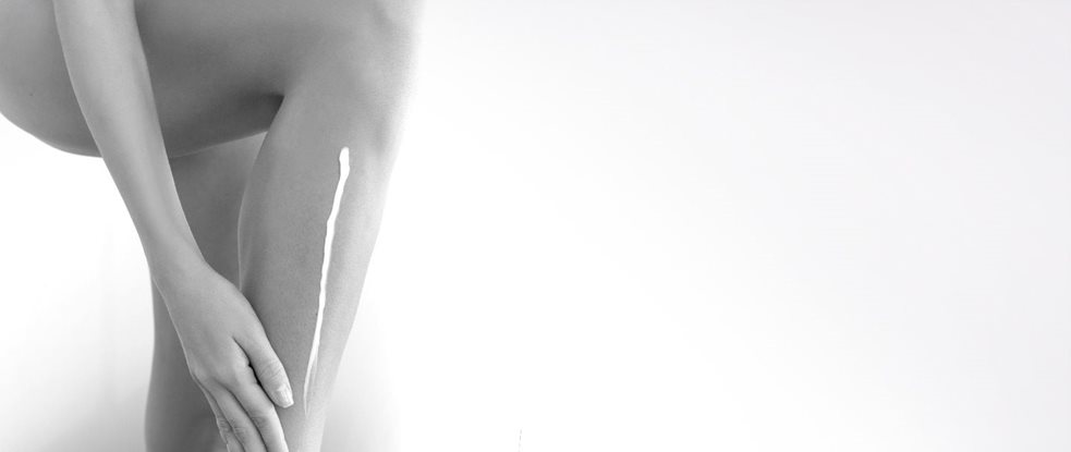 Woman applying creme on her leg.