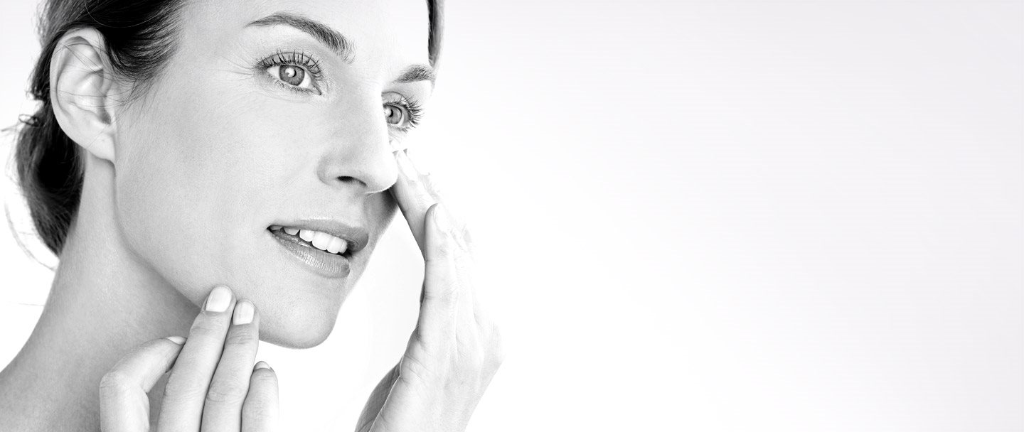 Woman applying cream on her cheek.