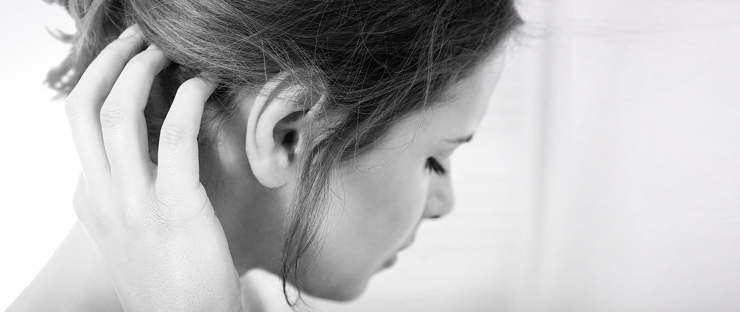 A woman in discomfort, touching her scalp